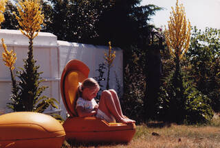 Girl sat in egg-shaped chair in a garden