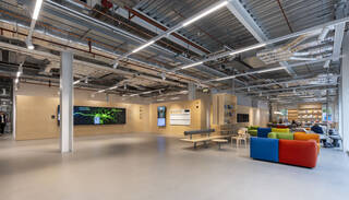 A large hallway space with seating on the right and a screen on a far wall displaying graphics